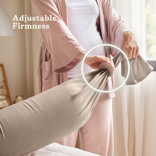 Person adjusting a beige bbhugme pregnancy pillow with text