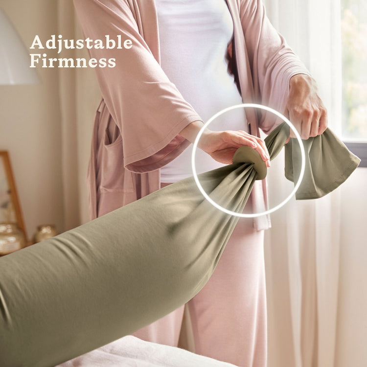 Person adjusting a green bbhugme pregnancy pillow with text 'Adjustable Firmness' in a bedroom setting.