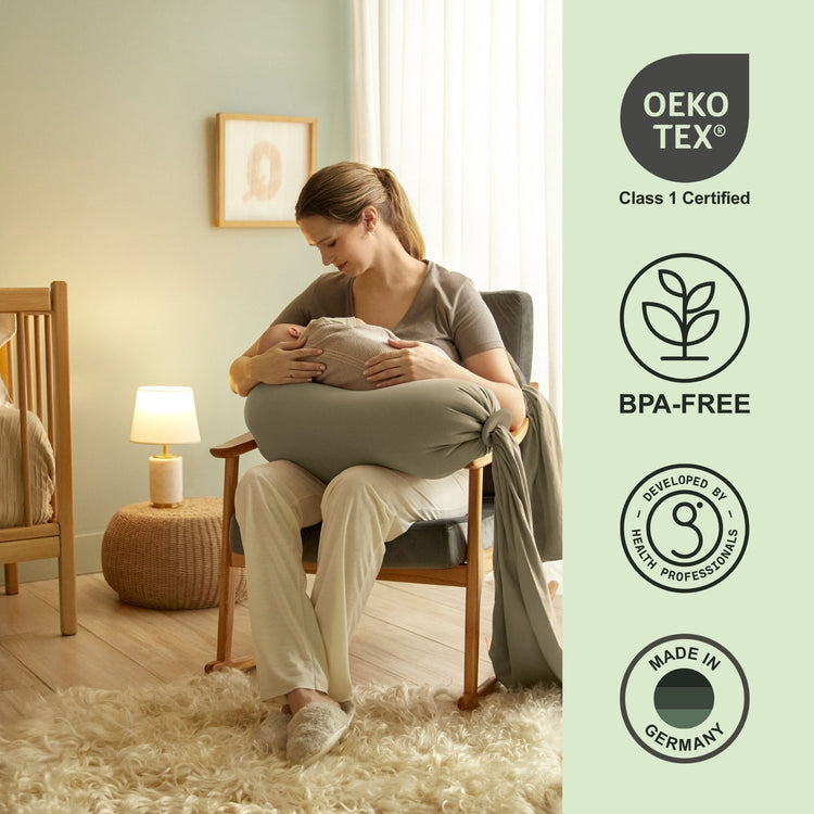 Woman holding a baby in a green cushioned chair with Oeko-Tex and BPA-Free certification icons on the right bbhugme pregnancy pillow